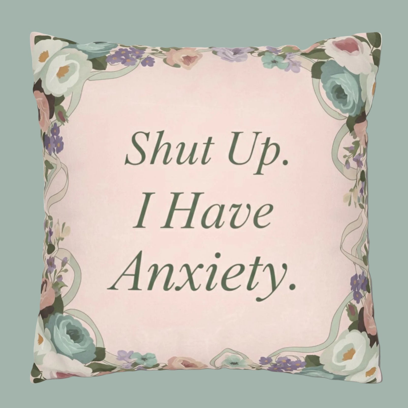 Decorative pillow with floral border and text 'Shut Up. I Have Anxiety.' on a light pink background