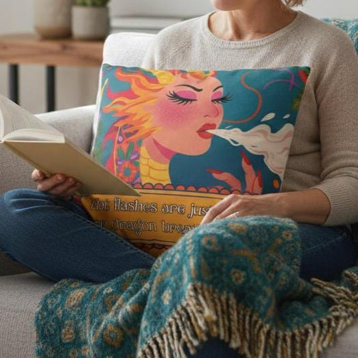Woman reading a book on a couch with a colorful pillow and blanket